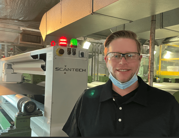 Matthew Baker beside an inline Scantech web measurement system during commissioning